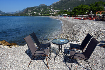 Fototapeta na wymiar Bar, Montenegro, Dalmatia, Balkans, Europe - chairs and table on characteristic pebbles beach, Adriatic Sea, Dinaric Alps