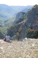 Naklejka premium Female hiker sitting on top of mountain and looking at landscape