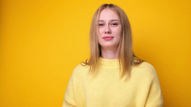 Cute girl sneezing and coughing on yellow background. The concept of a cold or allergies.