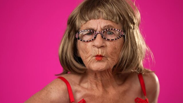 Closeup funny portrait of angry frustrated upset unhappy elderly old woman with no teeth isolated on pink background