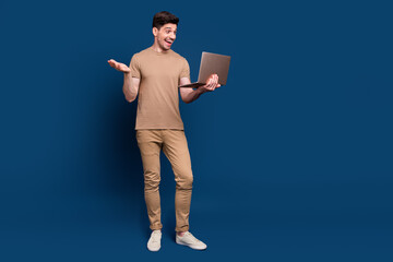 Full length photo of optimistic positive man wear beige stylish outfit look at laptop talk on...
