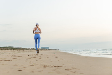 sportive woman running along beautiful sandy beach enjoying active summer near the sea