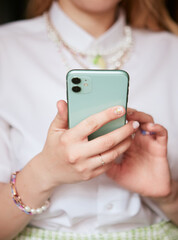 Close view of a girl holding a mint colored phone with the back side in her hands
