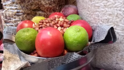 Almonds are kept in a vessel and salt is mixed in it and lemon and tomato are kept around it.
