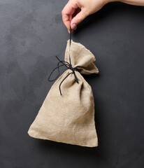 A woman's hand holds a canvas bag on a black background, the concept of a subsidy