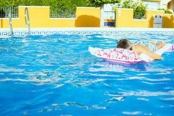 boy of European appearance is resting on pink inflatable mattress in the pool.Summer holiday concept