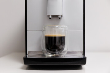 modern coffee machine with glass cup of espresso on the table at the kitchen