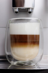 close up of double  glass cup of latte on coffee machine
