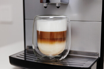 modern coffee machine with glass of fresh latte coffee