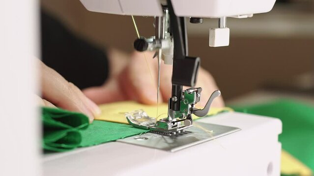 Close up footage of woman working on sewing machine in studio.