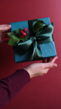Vertical video of woman holding Christmas or New Year blue gift box in her hands. Winter holiday greeting concept