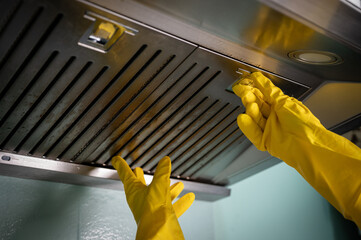 Housekeeping hands trying to removing a filters from cooker hood for cleaning it. - obrazy, fototapety, plakaty