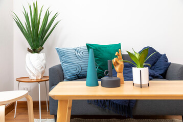 Modern living room with blue and green pillow on sofa. Coffee table with plant pot and ceramic vase.