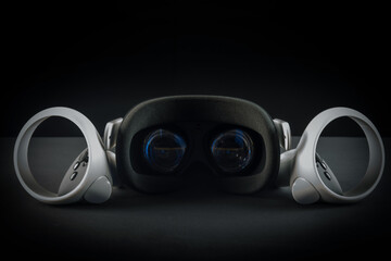 Virtual reality headset on a black background. VR glasses and video game controllers.