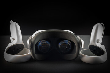 Virtual reality headset on a black background. VR glasses and video game controllers.