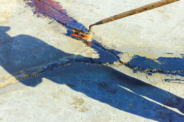 During repair work patcher applies coatings to asphalt cracks, seals them with bitumen emulsion...