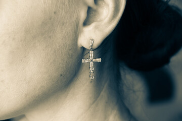 Earring in the form of a cross in a woman's ear, close