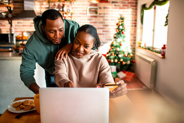 Young couple christmas shopping online at home