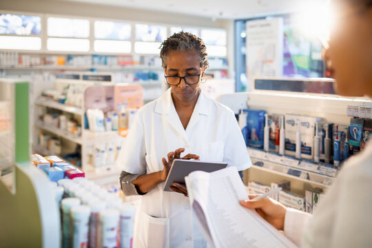 Senior female pharmacist doing inventory with colleague at drugstore