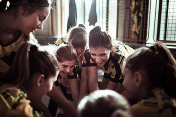 Female soccer players huddle together in unity in the locker room
