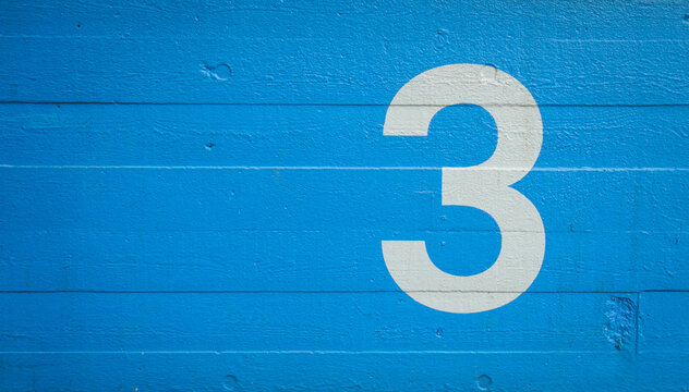 The number 3 painted on a blue concrete wall