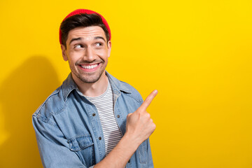 Photo of good mood excited guy wear denim jacket showing finger looking empty space isolated yellow color background