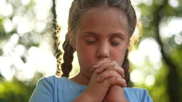 child pray. young gratitude a god religion concept. little girl in nature outdoors praying dreams of happiness to god. praise worship freedom concept. lifestyle kid praying in the forest