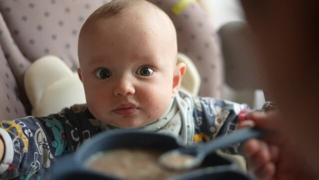 Healthy food. Cute baby boy face. beautiful a baby eats dirty. Healthy food family concept. mother feeds her daughter baby with a spoon, the child is dirty. newborn baby fun breakfast