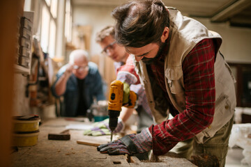 Three Men Engaged in Woodworking Project in Sunlit Workshop