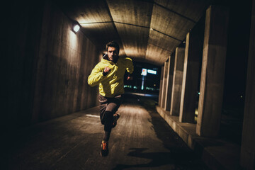 Focused Male Runner Sprinting in Urban Underpass at Night