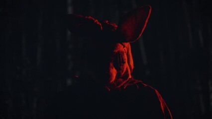 a murderer in a scary mask stands in a dark forest.