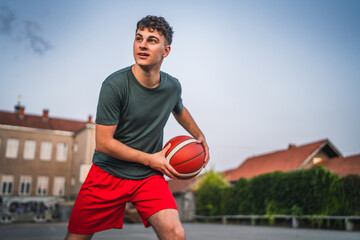 Fototapeta premium One caucasian teenager stand on basketball court with ball