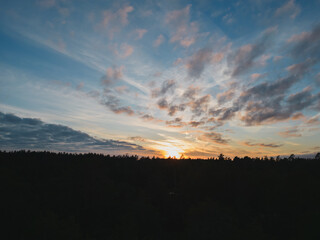 Nature of Estonia, sunset over the forest, silhouette of trees and sky in the clouds.