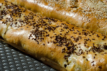 Meat pies. Baked rolls from yeast dough, sprinkled with sesame and flax seeds on parchment.