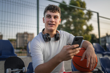 caucasian teen using mobile phone smartphone at a basketball court