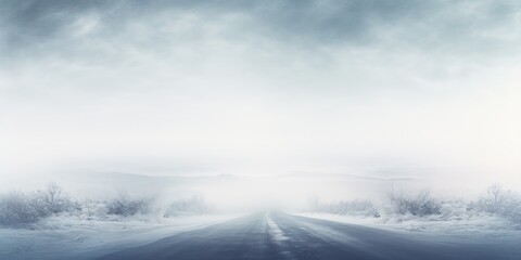A snowy road disappears into a foggy winter landscape.