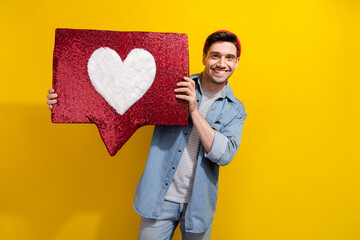 Photo of funky good mood guy wear denim jacket rising big heart like notification sign isolated yellow color background