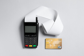 Payment terminal with thermal paper for receipt and credit card on light grey background, flat lay