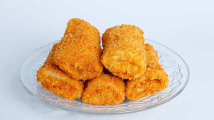 Spicy chicken risoles stuffed with chicken and chili and enclosed in crape-like wrappers and rolled into bread crumbs and fried. served on transparent plate and chili. selective focus.