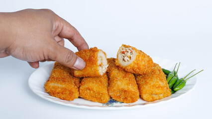 Spicy chicken risoles stuffed with chicken and chili and enclosed in crape-like wrappers and rolled into bread crumbs and fried. served on white plate and chili.