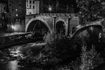 30 seconds water motion blur black and white picture of old stone bridge at night in the park,...