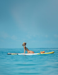 sexy girl in a swimsuit on a sup board lies resting on a board under the bright sun on the background of the sea , Stand up paddleboarding