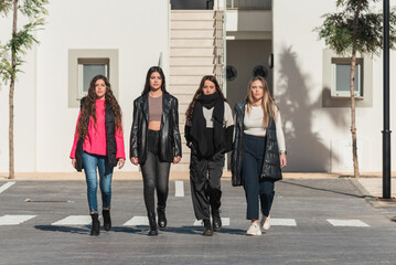 Fototapeta premium Group of girlfriends in warm clothes crossing road