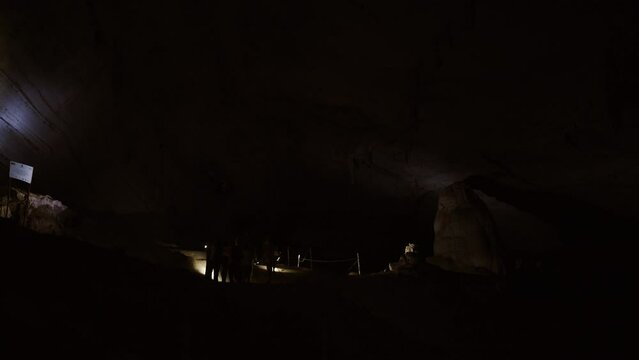 Group of People Exploring Dark Cave with Flashlights - Guided Tour Adventure .