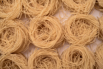 Texture of stacked vermicelli nests, still raw, delicious thin egg pasta on a white background.