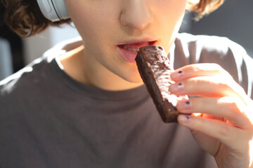 Woman eats chocolate bars snack between work.