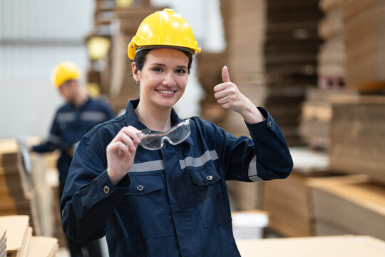 Portrait thump up Caucasian businesswoman with Kraft paper pack and buddy checking wood Kraft stock in warehouse	