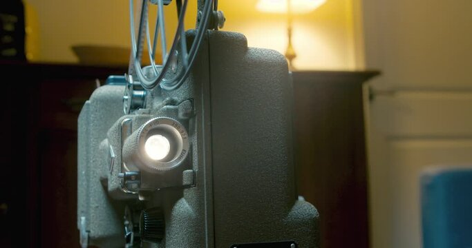 Vintage 8mm film projector spins a reel with a movie in the evening in home 