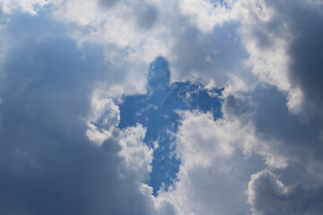 Gap in the clouds in the shape of a cross from the blue sky, heavenly symbol, atmospheric occurrence