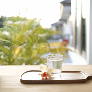 Glass of water and orchid flower on wooden tray